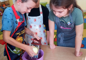 Dzieci ucierają jabłko na tarce.