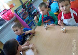 Dzieci smakują przy stolikach przygotowany deser z jabłuszkami.