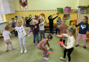 Dzieci tańczą z kolorowymi liśćmi.