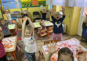 Dzieci pokazują swoje dłonie umalowane farbą.