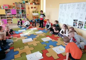 Dzieci układają kostki na talerzu zgodnie ze wskazaną liczbą oczek.