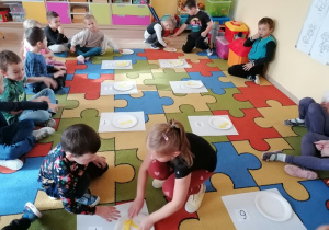 Dzieci układają kostki na talerzu zgodnie ze wskazaną cyfrą.