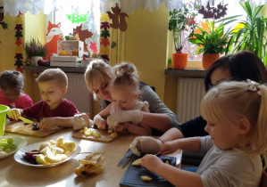 Dzieci z rodzicami wykonują sałatkę owocową