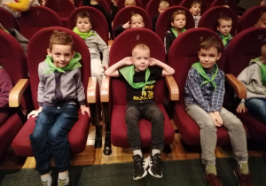Dzieci siedzą w fotelach w teatrze