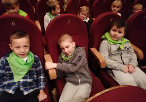 Dzieci siedzą w fotelach w teatrze