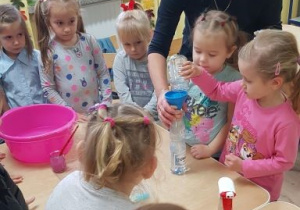 Dziewczynki przelewają wodę do butelki