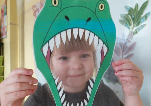 Dziewczynka robi zdjęcie z maską dinozaura