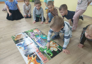 Chłopiec pokazuje na plakacie określonego dinozaura