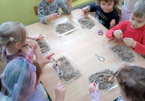 Dzieci odkrywają i oczyszczają wykopane elementy dinozaura