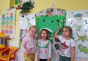 Dziewczynki pozują do zdjęcia z głową dinozaura