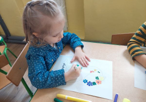 Dziewczynka dekoruje cyfrę 8 malując kredkami