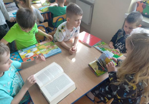 Czterech chłopców i dziewczynka oglądają różnego rodzaju książki
