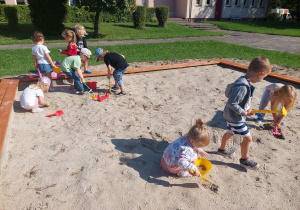 Grupa dzieci bawi się w piaskownicy