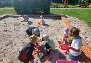 Grupa dzieci bawi się w piaskownicy