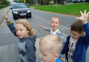 Dzieci podnoszą rękę do góry przechodząc przez ulicę