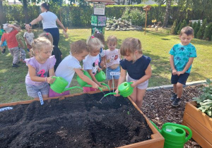Grupa dzieci podlewa miejsc posadzenia cebulek
