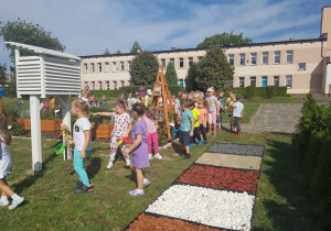 Dzieci w rytmie śpiewanej piosenki podążają do altany.