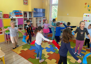 Dzieci tańczą z kolorowymi chustami, naśladując wirujące i spadające liście.