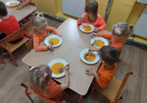 Dzieci na obiad jedzą zupę dyniową