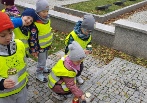 Dzieci kładą znicze na groby.