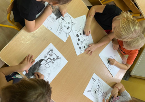 Dzieci rysują węglem kota.
