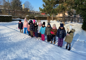 Dzieci obserwują i rozpoznają ślady na śniegu.