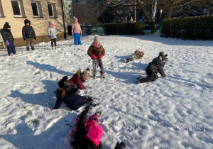 Dzieci turlają się na śniegu.
