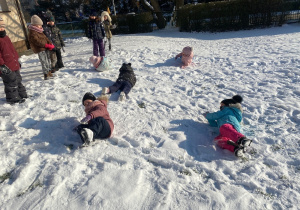 Dzieci turlają się na śniegu.