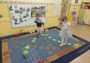 Dziewczynka i chłopiec chodzą po śladach dinozaura w poszukiwaniu zwierząt