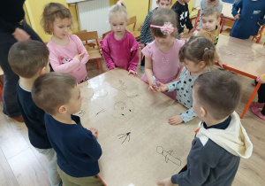 dzieci współpracując w grupie rysuje potworki