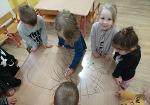 dzieci współpracując w grupie rysuje potworki