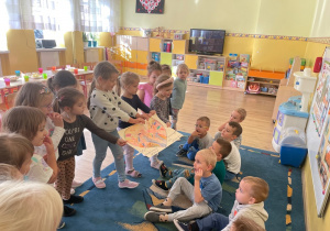 Grupa dziewczynek wręcza grupie chłopców rysunek serca. Atmosfera jest radosna.